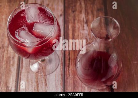 Blick von oben auf ein Glas Sommerrotwein auf den Felsen neben einer Karaffe auf einem Holztisch Stockfoto