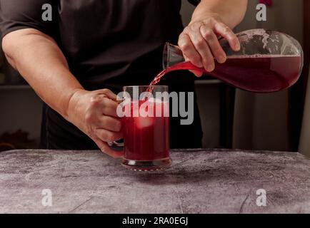 Eine in Schwarz gekleidete Kellnerin serviert einen Krug Sommerrotwein auf Eis aus einer Karaffe Stockfoto