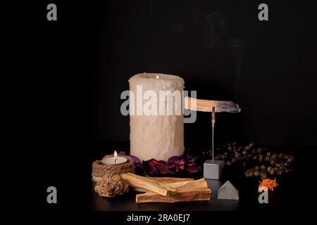 Palo santo (heiliger Stab) mit brennenden Kerzen und Japa mala auf schwarzem Hintergrund Stockfoto