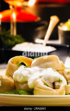 Russische Teigtaschen (Pelmeni) mit saurer Sahne (Smetana) und Fenchel, auf einen reichen Tisch Stockfoto