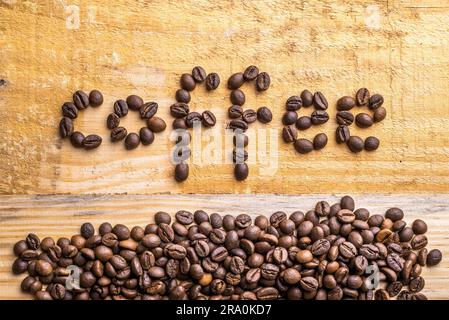 Heller Holzhintergrund mit Kaffeebohnen, die das Wort schreiben Stockfoto