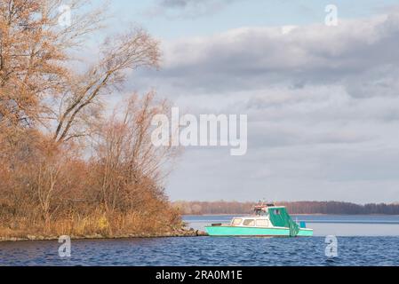 Ein grün Vintage Fischerboot am Dnepr in Kiew, Ukraine, bei stürmischen Herbst bewölktem Himmel Stockfoto