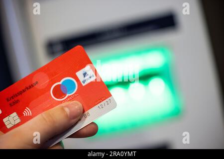 ILLUSTRATION - 23. Juni 2023, Nordrhein-Westfalen, Königswinter: Eine Bankkunden verwendet ihre Giro-Karte mit dem girocard-Logo (r) und dem rot-blauen Maestro-Logo (2-r), um Bargeld von einem Geldautomaten abzuheben. Die Maestro-Funktion der Giro-Karten, die Zahlungen und Barabhebungen im Ausland ermöglicht, wird in Zukunft nicht mehr auf neuen Karten verfügbar sein. Ab dem 1. Juli 2023 werden keine neuen Maestro-Karten mehr ausgestellt. (Zu dpa 'Girocard ohne Maestro: Was wird sich für Bankkunden ändern - und was nicht') Foto: Thomas Banneyer/dpa Stockfoto