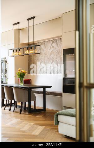 Küche und Essbereich mit Holzfußboden in der Mitte des Zimmers, durch eine offene Tür gesehen Stockfoto