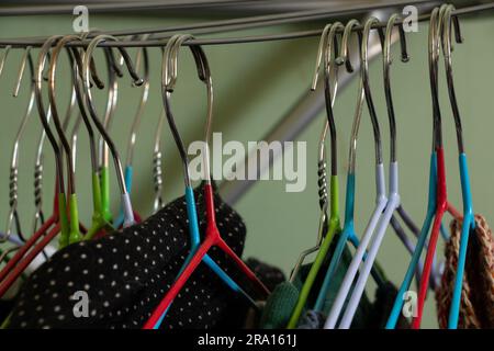 Verschiedene Kleidung auf Metallbügeln in einem Zimmer Stockfoto