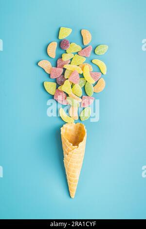 Mischung aus fruchtigen Gelee-Süßigkeiten und Eiskrem auf blauem Hintergrund. Draufsicht. Stockfoto