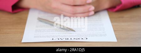 Geschäftsfrau, die einen Vertrag und einen silbernen Stift in die Hand legt Stockfoto