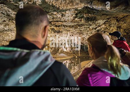 Touristen laufen in den Punkva (Punkevni) Höhlen, die mit Stalaktiten und Stalagmiten in Mährischem Karst, Tschechische Republik, geschmückt sind, 29. Juni 2023. (CTK Photo/Patrik Uhlir) Stockfoto