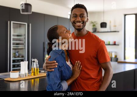 Porträt eines glücklichen afroamerikanischen Paares, das in der Küche umarmt Stockfoto