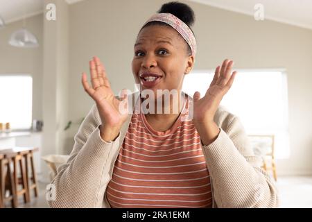 Glückliche afroamerikanische Frau, die am Tisch sitzt und Videoanrufe hat Stockfoto