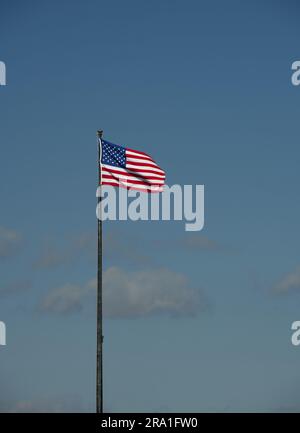 Amerikanische Flagge am Pol gegen blauen Himmel Stockfoto