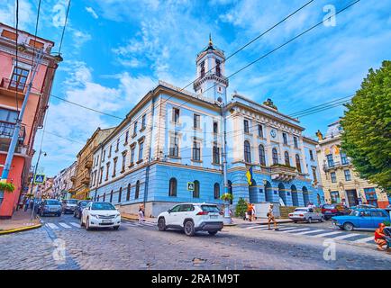 CHERNIVTSI, UKRAINE - 16. JULI 2021: Der belebte zentrale Platz mit viel Verkehr und altem Gebäude des Rathauses, am 16. Juli in Chernivtsi Stockfoto
