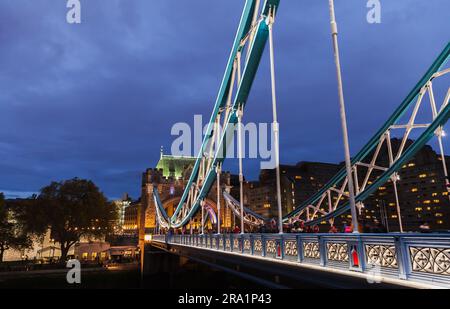 London, Großbritannien - 04. November 2017: Touristen gehen nachts über die beleuchtete Tower Bridge Stockfoto