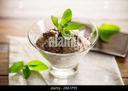 Hausgemachtes Eis mit Stücken geriebener dunkler Schokolade, in einer Schüssel auf einem Holztisch. Stockfoto