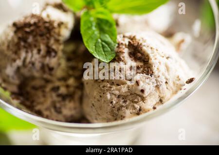 Hausgemachtes Eis mit Stücken geriebener dunkler Schokolade, in einer Schüssel auf einem Holztisch. Stockfoto