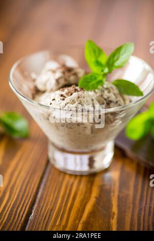 Hausgemachtes Eis mit Stücken geriebener dunkler Schokolade, in einer Schüssel auf einem Holztisch. Stockfoto