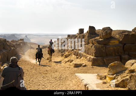 Männer reiten durch eine dünne Wüstenpassage in Kairo Ägypten Stockfoto