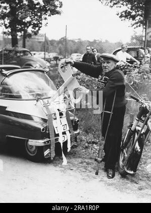 Das Berliner Original 'Krücke', bürgerlich Reinhold Habisch, zeiht mit Riesenschlüssel ein BMW Isetta auf. Berlin, Deutschland 1957. Stockfoto