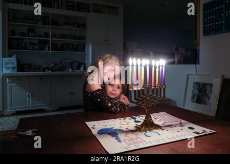 Zwei Schwestern stehen zusammen und sehen Chanukkah Menorah voll beleuchtet an Stockfoto