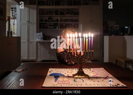 Zwei Schwestern stehen zusammen und sehen Chanukkah Menorah voll beleuchtet an Stockfoto