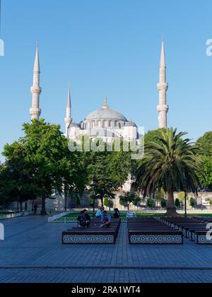 Touristen sitzen auf Bänken in den Gärten vor der Sulatn Ahmed Moschee aka Blaue Moschee, Sultanahmet Viertel, Istanbul, Türkei Stockfoto