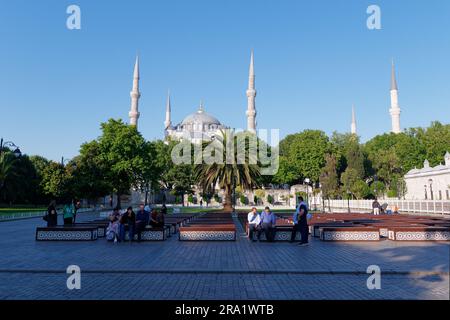 Touristen sitzen auf Bänken in den Gärten vor der Sulatn Ahmed Moschee aka Blaue Moschee, Sultanahmet Viertel, Istanbul, Türkei Stockfoto