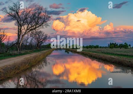 Luftaufnahme von farbenfrohen Gewitterwolken, die sich in den ruhigen Gewässern eines landwirtschaftlichen Kanals in St. George in Queensland, Australien Stockfoto