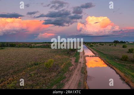 Luftaufnahme von farbenfrohen Gewitterwolken, die sich in den ruhigen Gewässern eines landwirtschaftlichen Kanals in St. George in Queensland, Australien Stockfoto