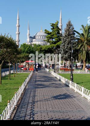 Gärten und Rote Karren, die Simits aka türkische Bagels verkaufen, mit der Sultan Ahmed aka Blaue Moschee dahinter, Sultanahmet Viertel, Istanbul, Türkei Stockfoto