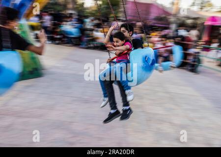 Idlib, Syrien. 29. Juni 2023. Syrische Kinder fahren auf einem Schaukelkarussell im Stadtpark während der Feierlichkeiten des Eid al-Adha-Urlaubs in Idlib. Eid al-Adha ist das heiligste Fest im Islam, bei dem Muslime Rinder und Schafe schlachten, um der Bereitschaft des Propheten Ibrahim (Abraham) zu gedenken, seinen Sohn Ishmael zu opfern. Kredit: Anas Alkharboutli/dpa/Alamy Live News Stockfoto