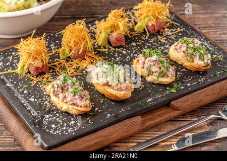 Bruschetta mit Meeresfrüchten mit asiatischen Aromen auf einem Steinschneidbrett Stockfoto