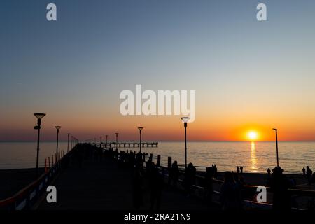 Viele Leute am Pier bei Sonnenuntergang. Statische Aufnahme während eines wolkenlosen Abends Stockfoto