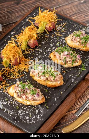 Bruschetta mit Meeresfrüchten mit asiatischen Aromen auf einem Steinschneidbrett Stockfoto