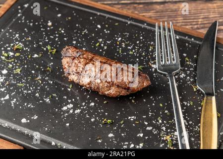 Fleischklößchen mit gegrilltem Cheddar auf einem Steinschneidebrett im Steakhouse-Restaurant Stockfoto