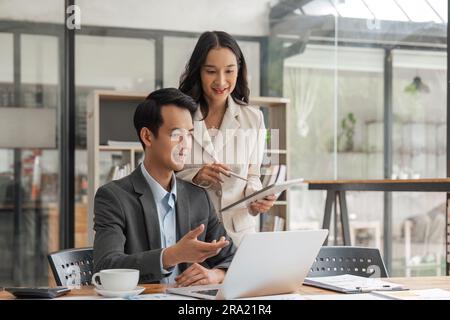 geschäftsführer ceo, der mit einer Kollegin spricht, mit einem Laptop und einem Tablet über den Geschäftsplan bei einer Besprechung im Vorstand Stockfoto