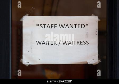 Papier wurde im Fenster eines Restaurants mit der Aufschrift "Personal gesucht: Kellner / Kellnerin" verputzt. Stockfoto