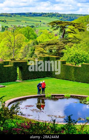 Zwei Besucher genießen die friedliche Ruhe des ruhigen Wassers im kreisförmigen Pool Garden am Knightshayes Court, nr Tiverton, Devon, England, Großbritannien Stockfoto