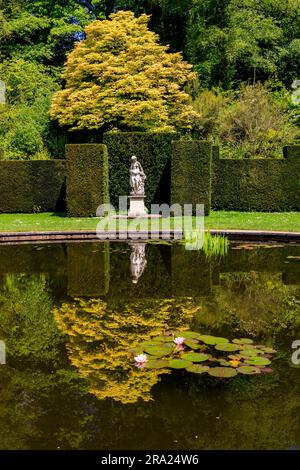 Reflexionen der Statue im stillen Wasser des kreisförmigen Pool Garden am Knightshayes Court, nr Tiverton, Devon, England, Großbritannien Stockfoto