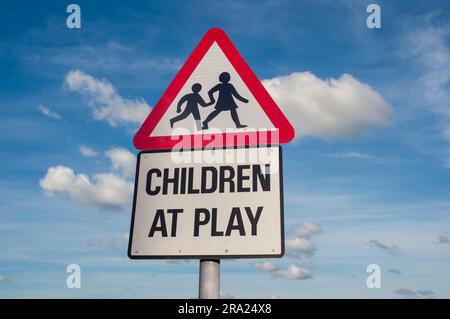 Kinder spielen Straßenschild vor blauem Himmel Stockfoto