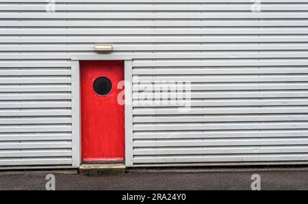 Graues Industriegebäude mit roter Tür Stockfoto