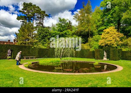 Zwei Besucher genießen die friedliche Ruhe des ruhigen Wassers im kreisförmigen Pool Garden am Knightshayes Court, nr Tiverton, Devon, England, Großbritannien Stockfoto