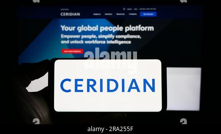 Person, die ein Smartphone mit dem Logo des US-amerikanischen Softwareunternehmens Ceridian HCM Holding Inc. Auf dem Bildschirm vor der Website hält. Konzentrieren Sie sich auf das Display des Telefons. Stockfoto