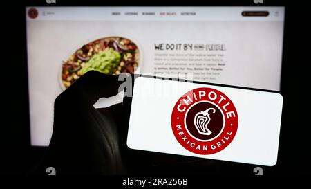 Person, die ein Smartphone mit dem Logo des US-Unternehmens Chipotle Mexican Grill Inc. Auf dem Bildschirm vor der Website hält. Konzentrieren Sie sich auf das Display des Telefons. Stockfoto