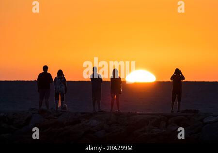 Menschen am Venice Jetty, die von der Sonne über dem Golf von Mexiko in Venice, Florida, USA, umgeben sind Stockfoto