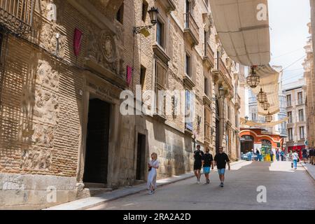 Toledo, Blick im Sommer auf Menschen, die am Erzbischofspalast in der Calle Arco de Palacio in der historischen Altstadt von Toledo, Spanien, vorbeigehen Stockfoto