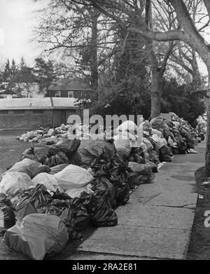 Bürgersteig in Wohngemeinde, mit Plastiktüten voller Müll, die hoch gestapelt sind. Offensichtliche Müllstreik-Situation Stockfoto