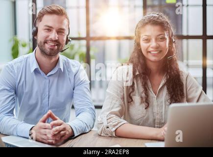 Lächelnder Mann und charmante Frau sitzen in Kopfhörern vor Laptops Stockfoto