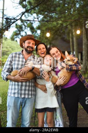 Familienmitglieder, Vater, Mutter und zwei Töchter mit Corgi-Hunden im Wald Stockfoto