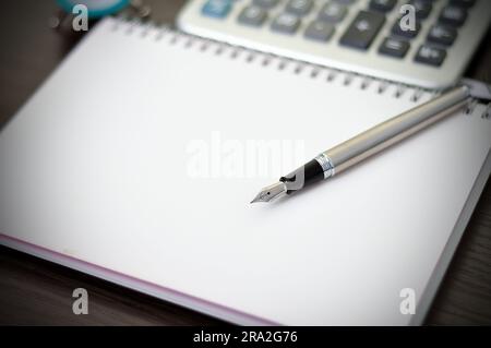 Füllfederhalter auf Notizbuch und Taschenrechner Stockfoto