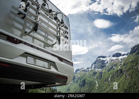 Moderner, halbintegraler Camper-Van auf dem Roadtrip. Rückansicht mit malerischen Bergen im Hintergrund. Fahrradständer – Nahaufnahme. Stockfoto